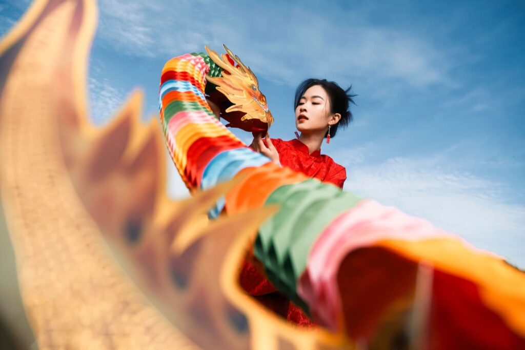 Chinese girl dancing the dragon dancing the background is a blue sky with clouds on top